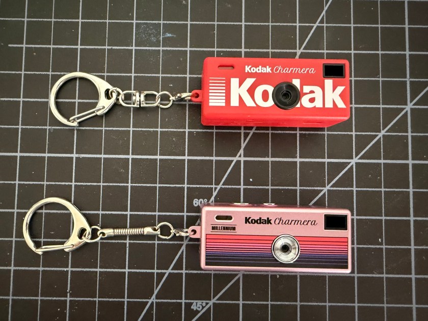 two kodak charmera cameras. the top one is red and the bottom one is a shiny metalic pink.